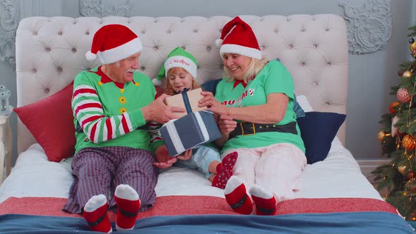 Senior Grandparents with Granddaughter Girl Kid Exhcanging Gifts at Home Bedroom Near Christmas Tree