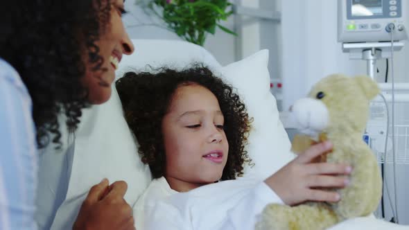 Close-up of African american mother and son playing with teddy bear in the ward at hospital 4k