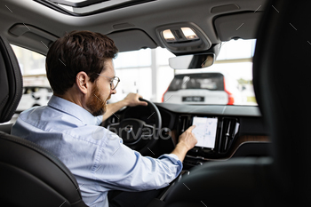 Businessman using touchscreen inside car at dealership