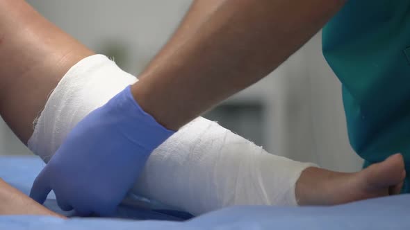 Doctor Putting Roller Bandage on Patient Leg, Medical Treatment in Hospital