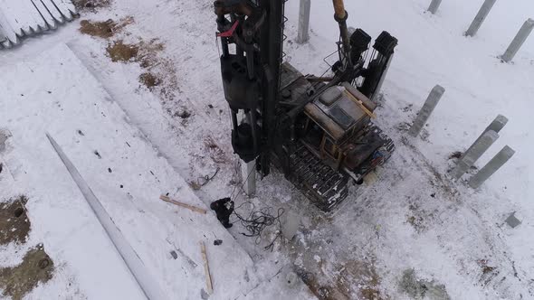 Aerial drone view of a pile bore machine at work at winter construction site 09