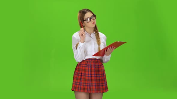 Schoolgirl with Glasses Writes on White Paper. Green Screen