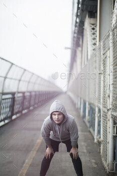 Focused athlete preparing to sprint on a misty bridge