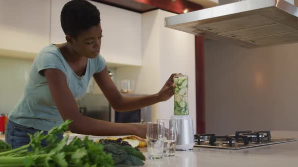 African american attractive woman blending ingredients for smoothie in kitchen