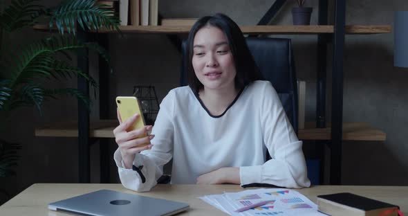 Young Asian Woman Making Video Call Chat Online on Mobile Phone in Modern Office