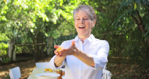 Senior woman tossing lemon