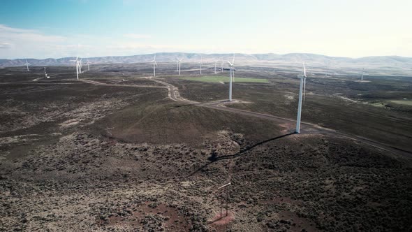 Slowly rising up revealing a large wind powered electric generating wind turbine green farm, aerial