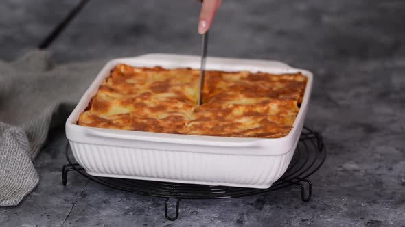 Hand Cutting a Homemade Chicken Lasagna Freshly Baked