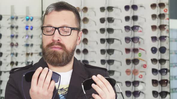 Mature Man Choosing Between Two Pairs of Sunglasses at the Store