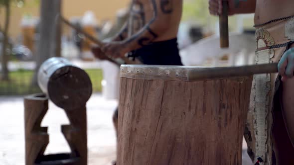 Extreme closeup of Mayan or Aztec drummers playing wooden drums with animals skins and sticks in a p