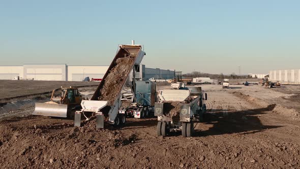 A dump truck full of dirt on a construction site drops its load.