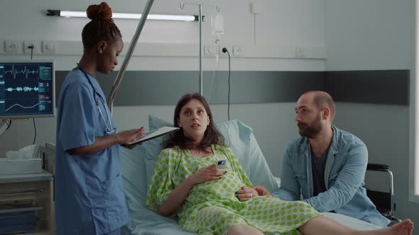 African American Nurse Using Tablet for Pregnant Patient Healthcare