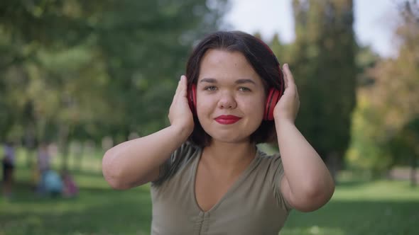 Portrait of Relaxed Caucasian Young Woman with Dwarfism Listening to Music on Headphones Smiling