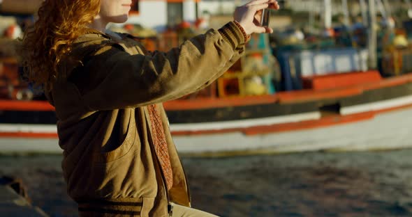 Woman clicking photos with mobile phone at dock 4k