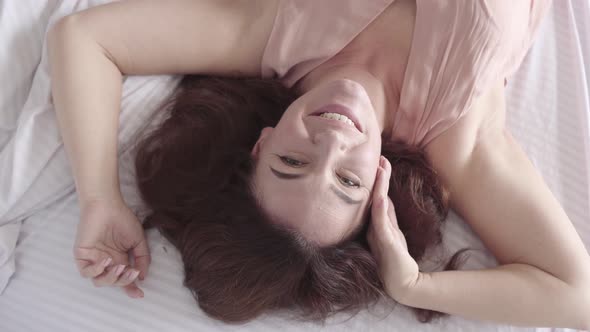 Portrait of Cute Mature Woman Lying on the Bed Looking at the Camera