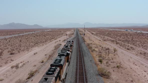 A freight train moves across the desert from a high angle.