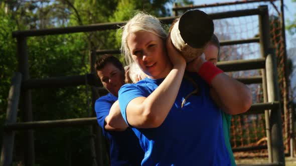 Group of fit women carrying a heavy wooden log during obstacle course