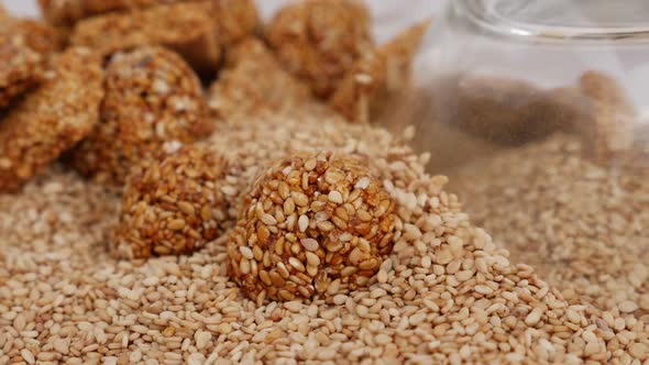 Micro shot of dropping sesame seeds over a ladoo isolated on white background