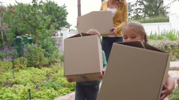 Mother and children carrying cardboard boxes towards home 4k