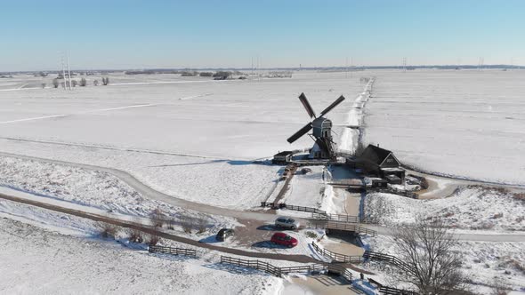 Aerial shot of Dutch windmill in white snowy countryside, winter landscape scene