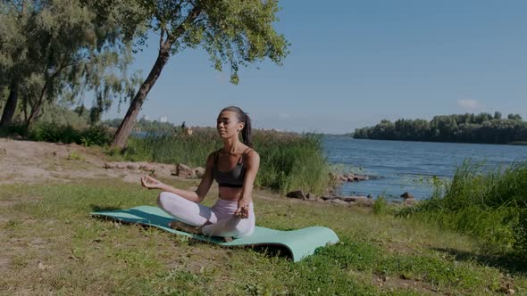 Young African Woman in Lotus Yoga Position Sitting Outdoors Near the River