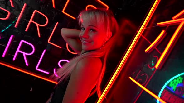 Joyful Go-go Dancer Woman Is Flirting with Camera, Portrait Against Signboard of Nightclub with Neon