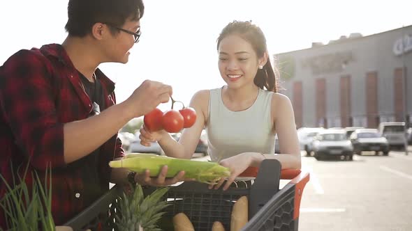 Vietnamese Man Showing Her Cute Girlfriend Corn and Tomatoes Which Get Out from Market Trolley