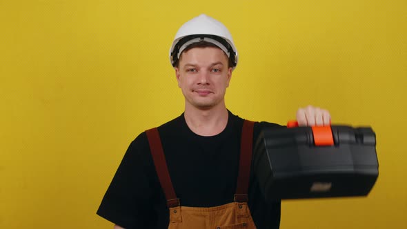 Happy Worker in Uniform and Hard Hat Holding Tool Box and Showing Thumbs Up