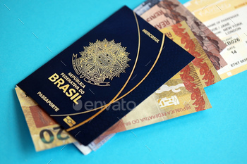 Blue Brazilian passport with money and airline tickets on blue background close up