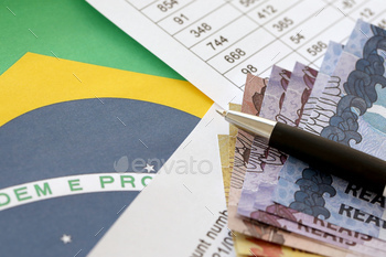 Pen with Brazilian money bills on blank of lottery game. Concept of luck and gambling in Brazil