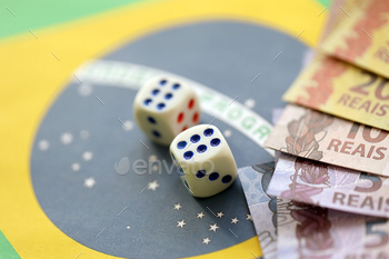 Dice cubes with brazilian money bills on flag of Brasil Republic