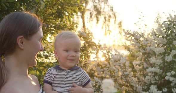 Happy Mother Playing with Toddler Kissing Him and Having Joy with Tree's Bloom