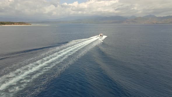 Aerial tracking shot of speedboat passing the Indian Ocean during sunny and cloudy weather.