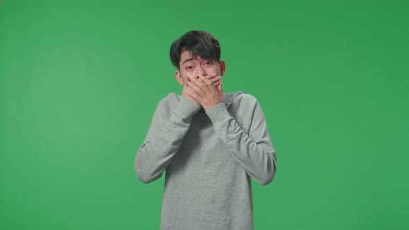 Asian Man Surprised While Standing In Front Of Green Screen Background