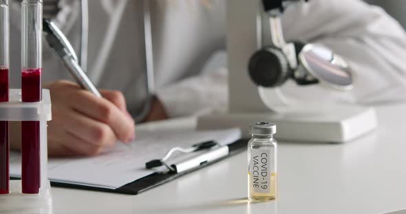 COVID-19 Vaccine, The Lab Worker Is Filling Out the Documents, A Microscope and Test Tubes Are in