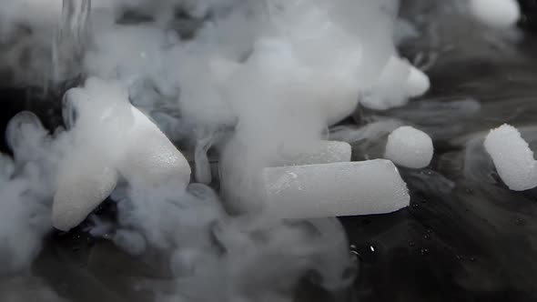 Dry Ice on Dark Surface Onto Which Water Drips and It's Chemical Reaction Produced Smokes. Slow