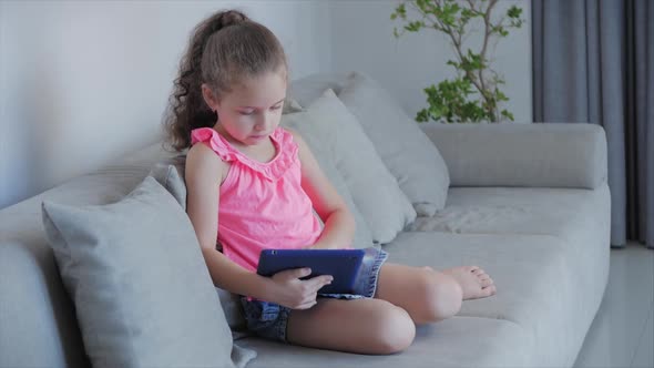 Curious Cute Kid Little Girl Using Digital Tablet Technology Device Included in Studies Sitting on