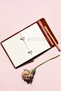 Open notebook with blank pages, pen and dried flower. Creativity and writing concept.