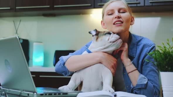 Pretty Woman Reading Something on Laptop and Playing with Cute Bulldog