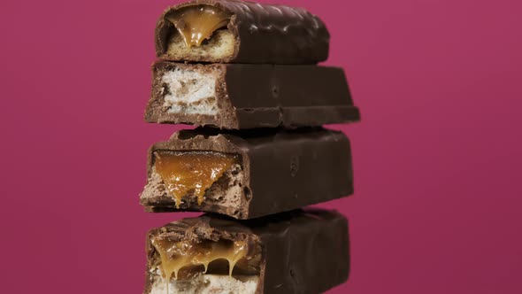 Four Candy Bars Spin on Pink Background. The Unpacked Sweets Close Up Macro Shot. Nougat and Caramel