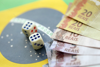 Dice cubes with brazilian money bills on flag of Brasil Republic