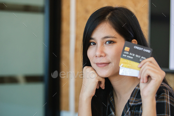 Asian female holding credit card. Beautiful smiling showing credit card to online payment