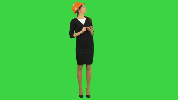 Female Engineer in Helmet Using Phone To Take Photo of Construction on a Green Screen, Chroma Key.