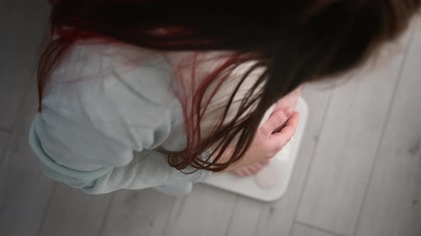 Young Woman Measuring Her Pregnant Weight Standing on Scales