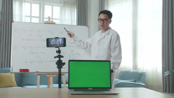 Asian Male Teacher With Green Screen Laptop Shoots Video By Smartphone Camera While Teaching Chemist