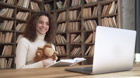 Smiling Hispanic Teacher Reading Book During Virtual Online Kindergarten Class