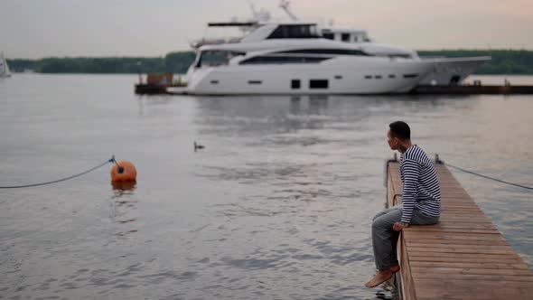 Young Romantic Man is Admiring Sunrise in Pier in Calm Morning Marine Landscape and Sailor