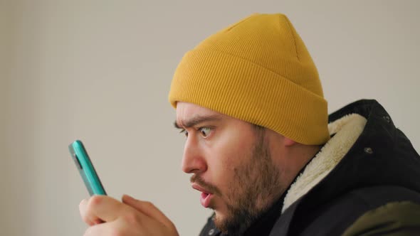 Close Up of a Crazy and Funny Face of American Bearded Man Addicted to Play Mobile Game