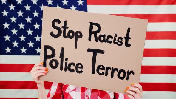 Protester Holds a Banner with a Slogan - Stop Racist Police Terror - Against Background of the USA