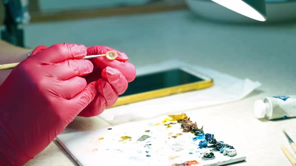 Medical worker painting artificial eye prosthesis.